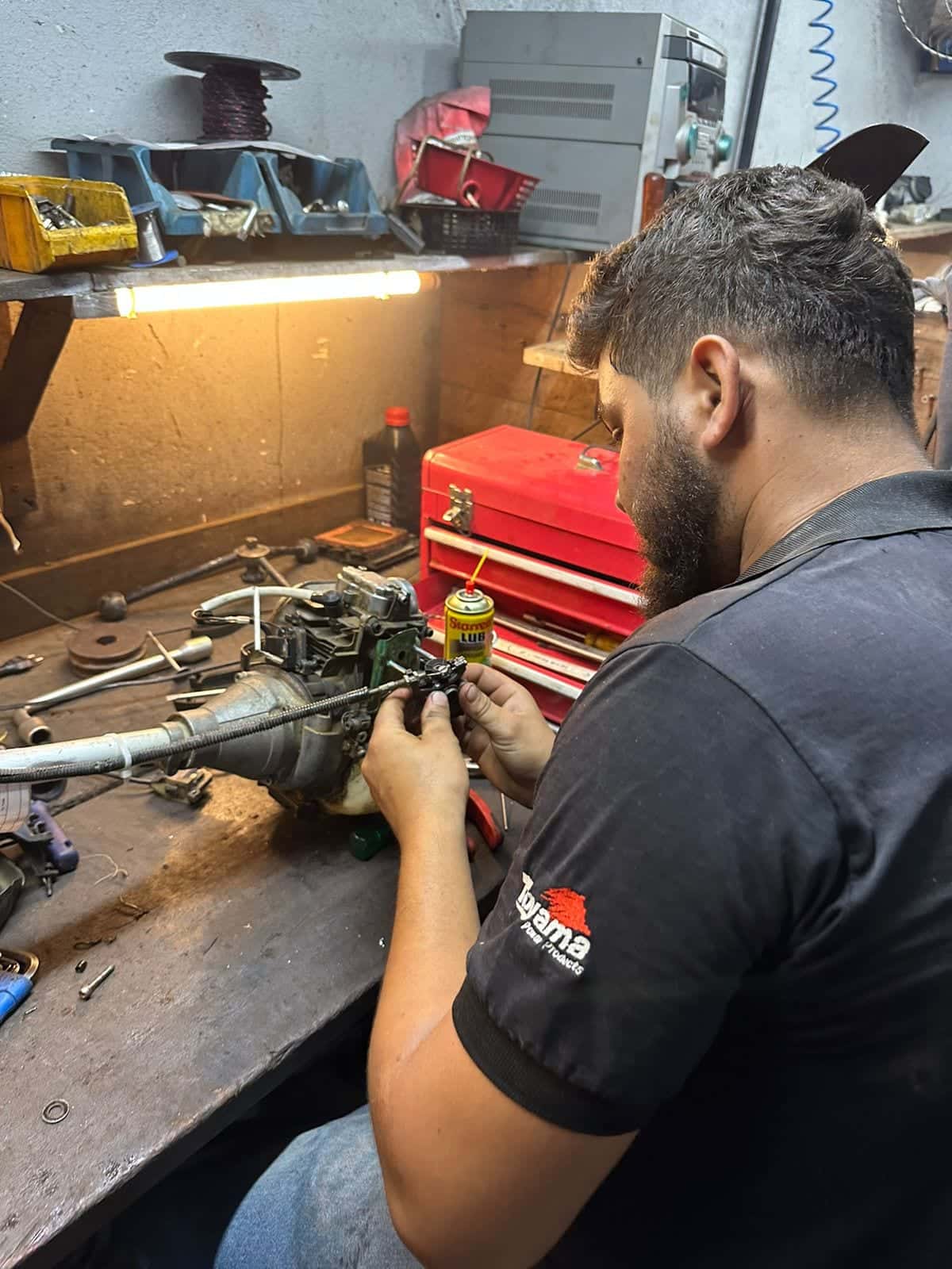 Técnico consertando o carburador de um motor na bancada da oficina
