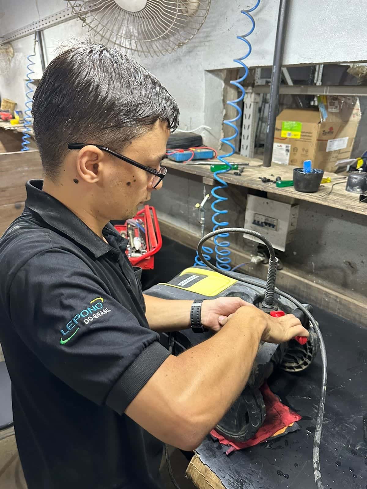 Técnico consertando uma lavadora de alta pressão na oficina