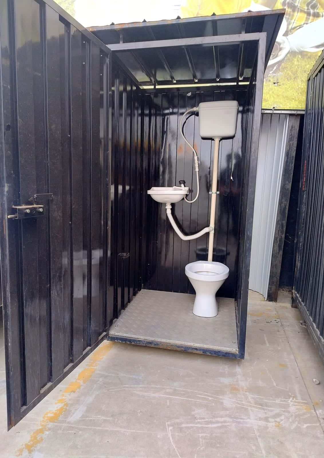 Banheiro da Ricieri com a porta aberta, mostrando o vaso, a pia e a caixa de descarga dentro do módulo preto