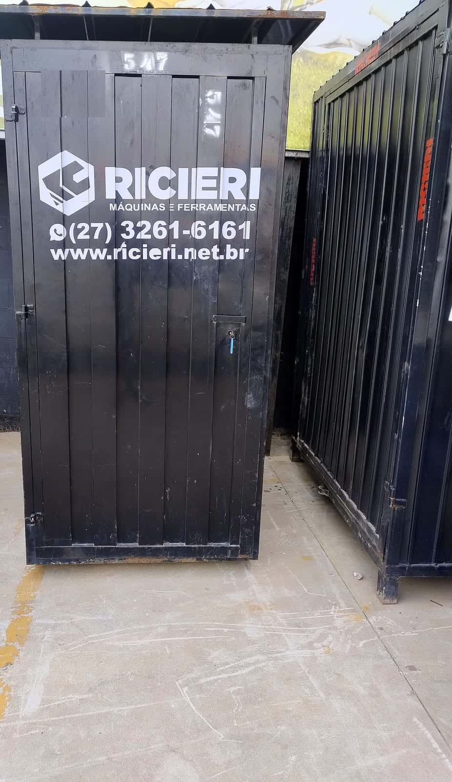 Banheiro da Ricieri fechado, visto de frente, com o logotipo e o telefone da empresa na porta