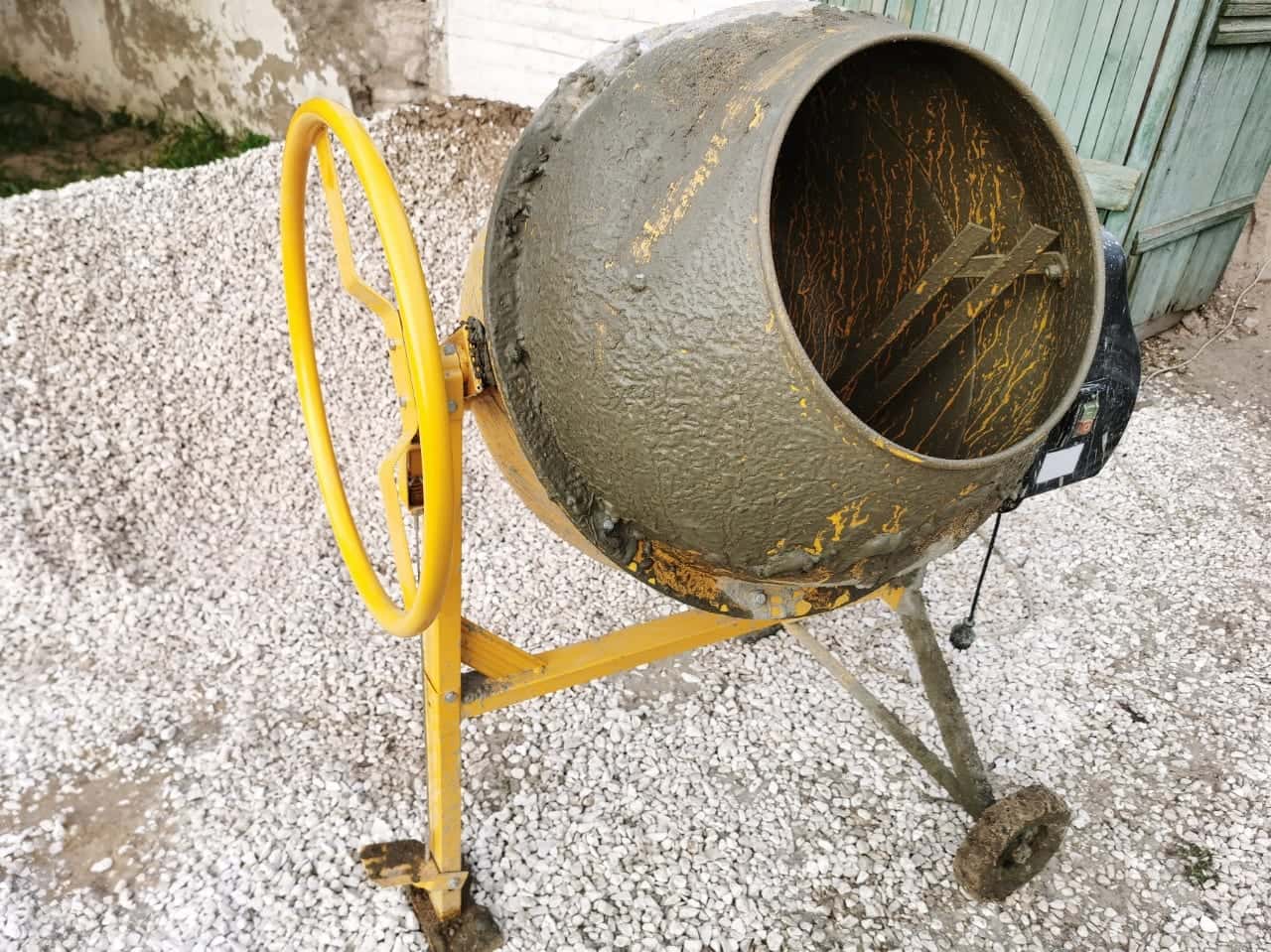 Betoneira amarela de 150 litros em uso numa obra, sobre brita